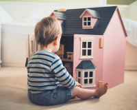 boy sitting in front of a dolls house