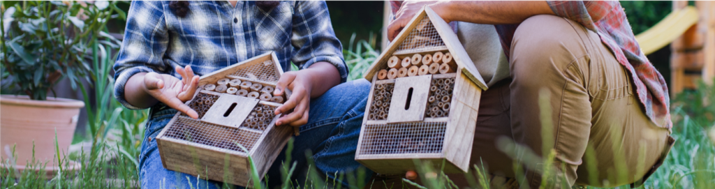 Two people holding small bug hotels